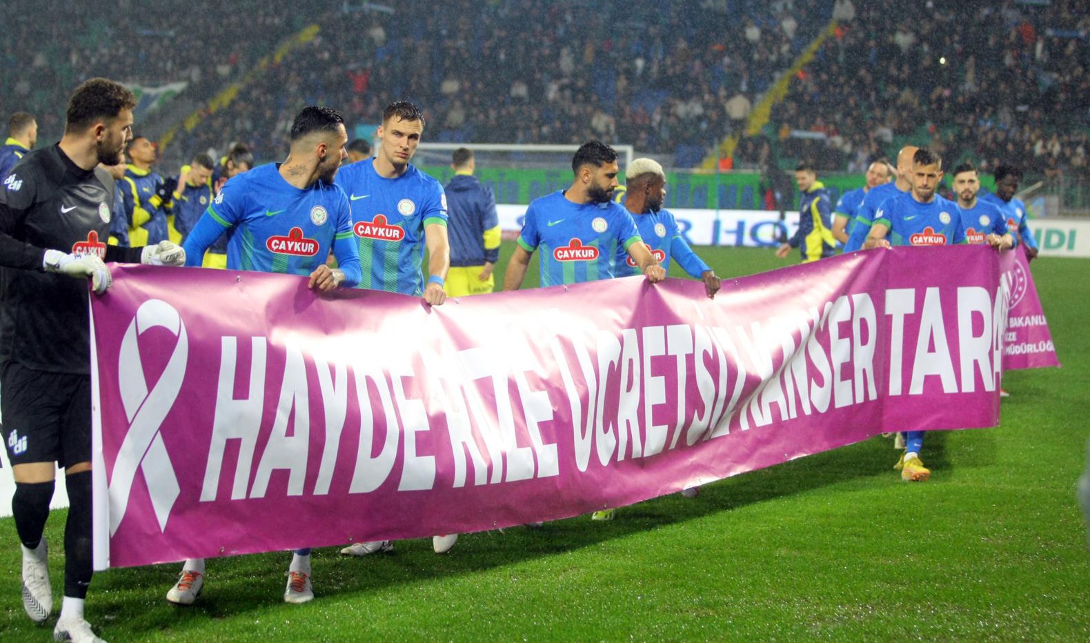 Rizesporlu futbolcular “Hayde Rize, Ücretsiz Kanser Taraman İçin Ketem’e Gel!” pankartıyla sahaya çıktı