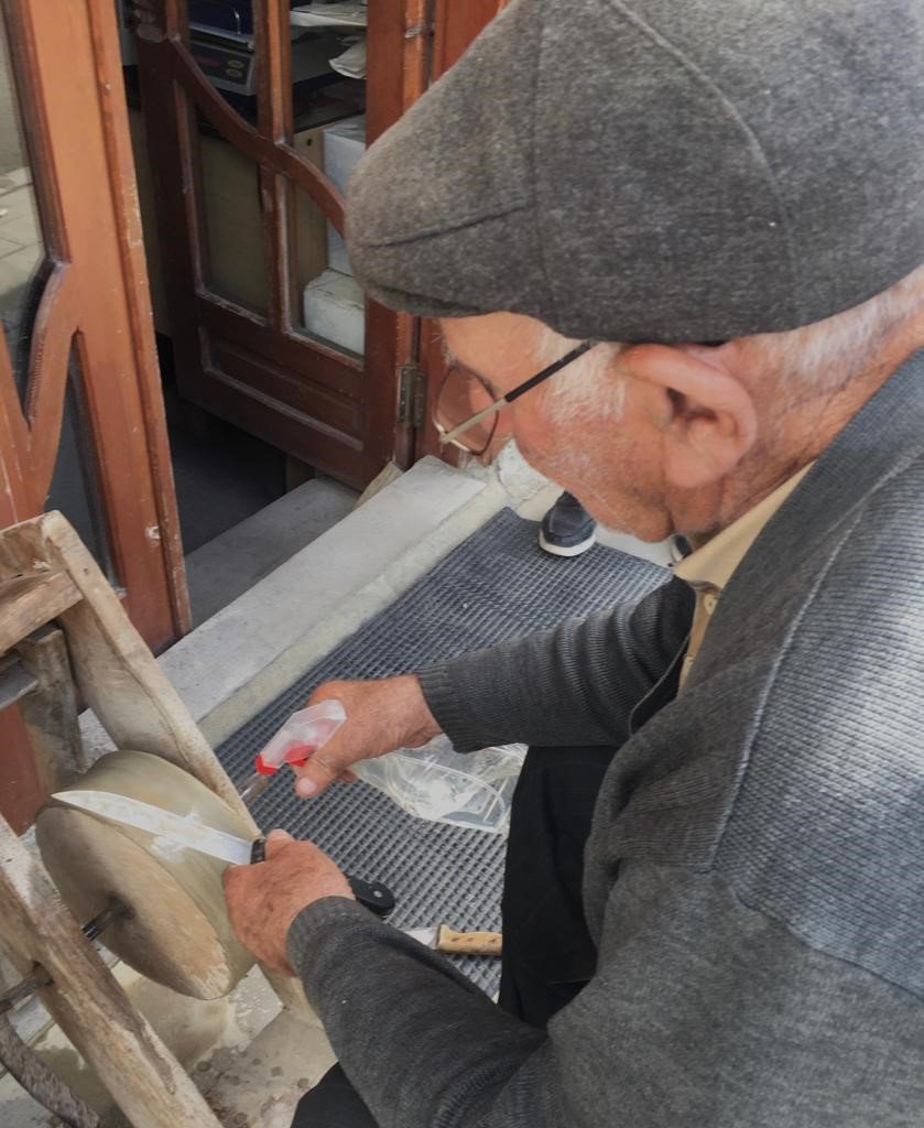 ERZURUM'UN ŞENKAYA İLÇESİNDE ESNAFLIK YAPAN 87 YAŞINDAKİ ÖZAY DEDE (HEKİMOĞLU), KURBAN BAYRAMI ÖNCESİ ÇEVİRMELİ "ÇARK TAŞI" TEZGAHINDA BIÇAKLARI BİLEVLİYOR