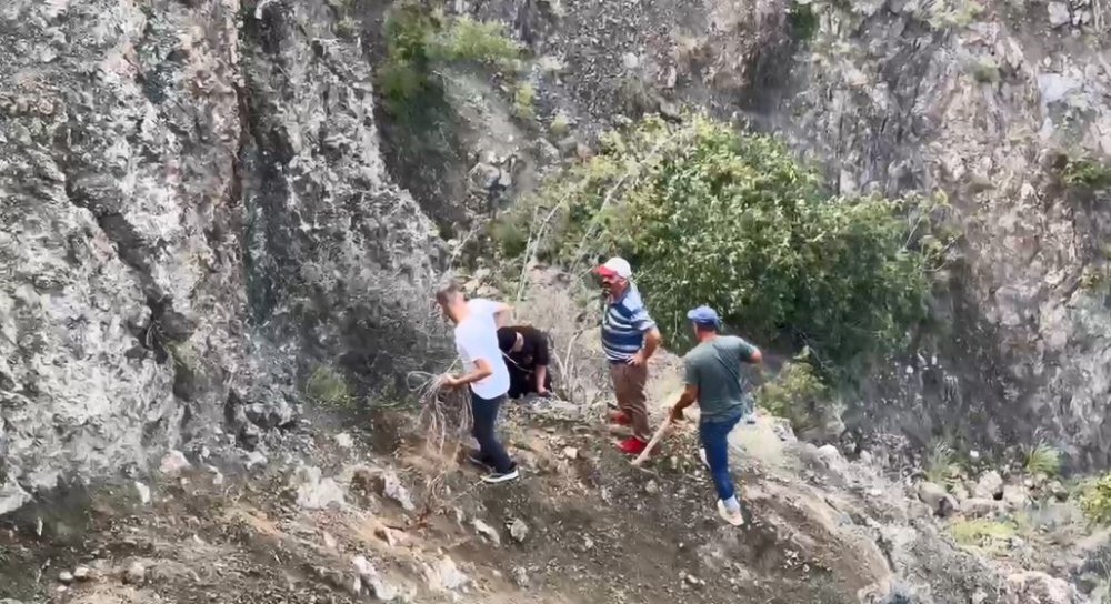 Artvin'de kapalı olan köy yolunu kepçe yardımıyla geçiyorlar