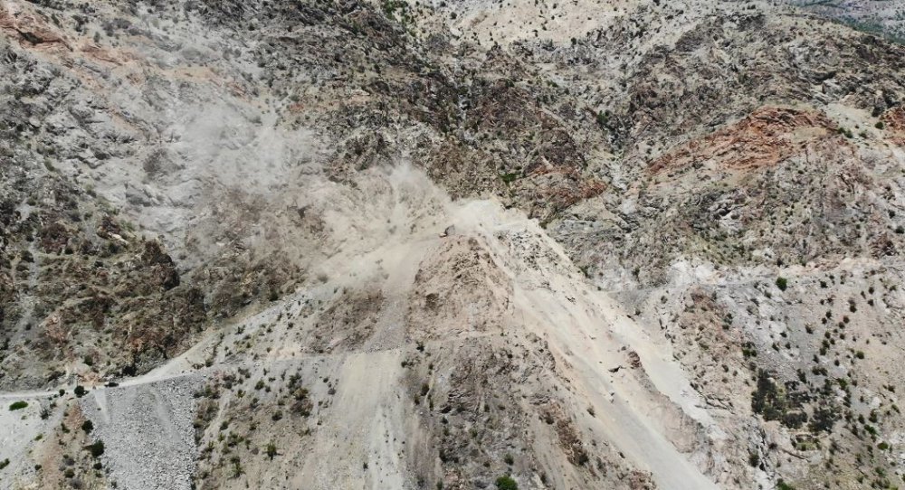 Artvin'de kapalı olan köy yolunu kepçe yardımıyla geçiyorlar