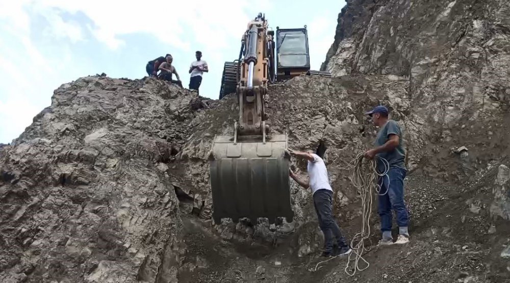 Artvin'de kapalı olan köy yolunu kepçe yardımıyla geçiyorlar